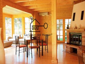 comedor salón diáfano de interior de casa de madera con vigas vistas y suelo de tarima