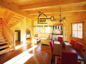 salón-comedor con vigas vistas y escalera abierta de madera