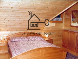 dormitorio de matrimonio con mansarda, paredes acabadas en madera